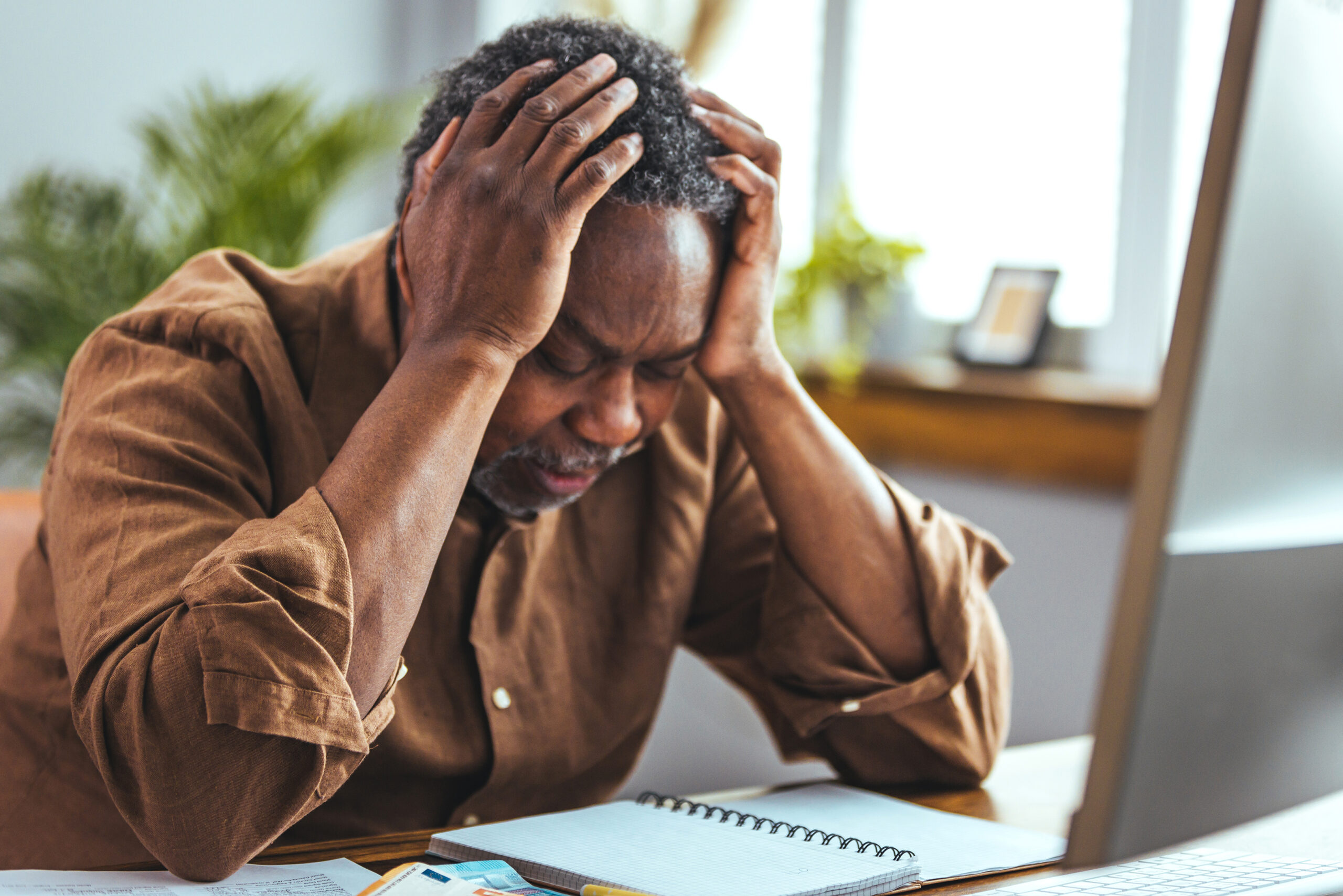 Distraught Older Man at Table with Laptop